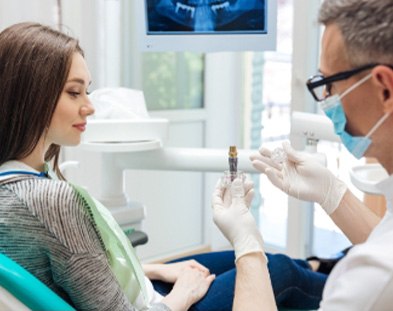 team member showing implant model to patient in Family Dental Center of East Texas   